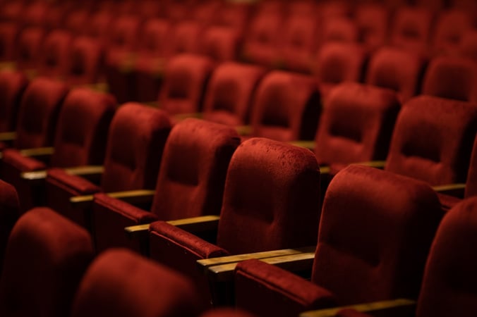 Rows of red traditional theatre seats stand empty