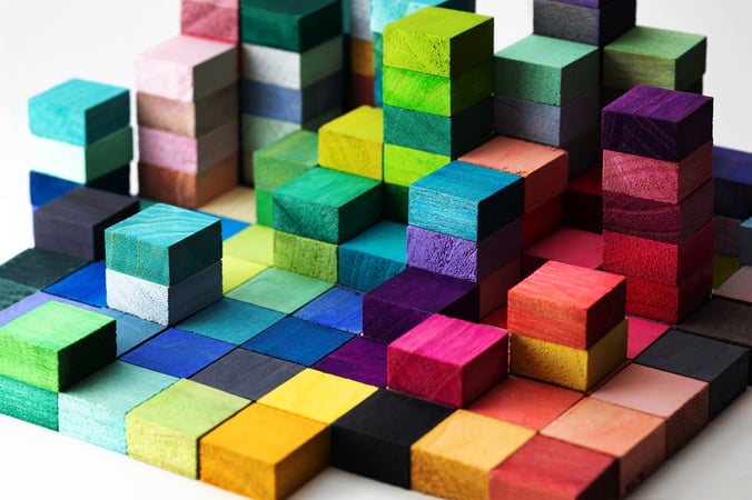Wooden blocks of many different colours, stacked into a pile