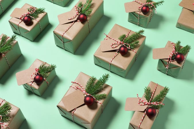 A number of gift boxes, wrapped with brown paper, holly and red bells