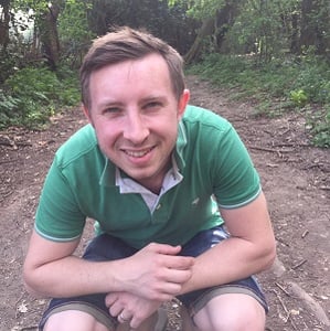 A crouching picture of Richard Homewood, a man with brown hair in the local forest.
