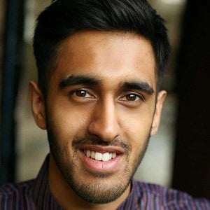 A headshot of Huzeifa Hussein.  A man with black hair, wearing a wear a traditionally indian kurta and smiling, whilst looking into camera