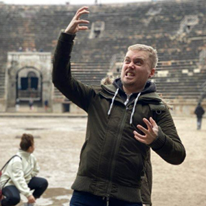Mark Beards, a 30-something white man, is pratting about in an amphitheatre, pretending hes in a daft metal band
