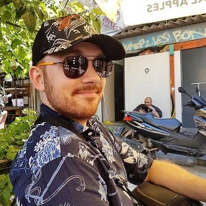 Robin Dodds sitting in a cafe on a Greek island looking happy wearing clothes with heavily clashing patterns.