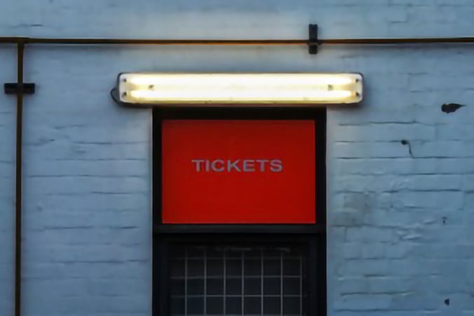 A ticket office window with an illuminated light above its sign