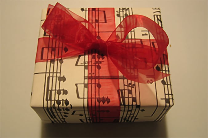 A gift wrapped in paper printed with musical notation, and tied with a red bow
